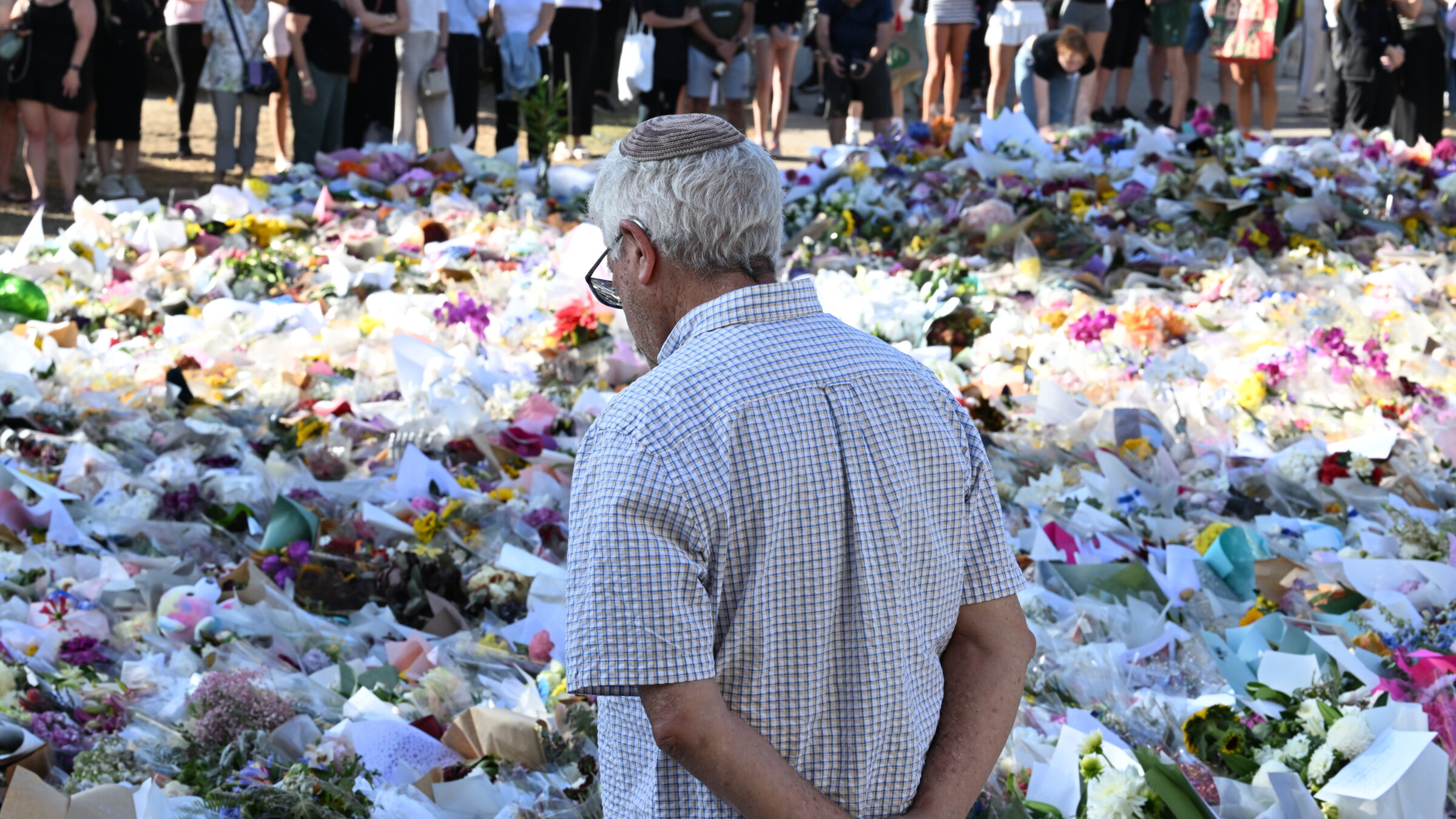 אַ ייִד שטייט בײַם דענקמאָל לעבן דעם באָנדי־ביטש פּאַוויליאָן, דעם 17טן דעצעמבער 2025