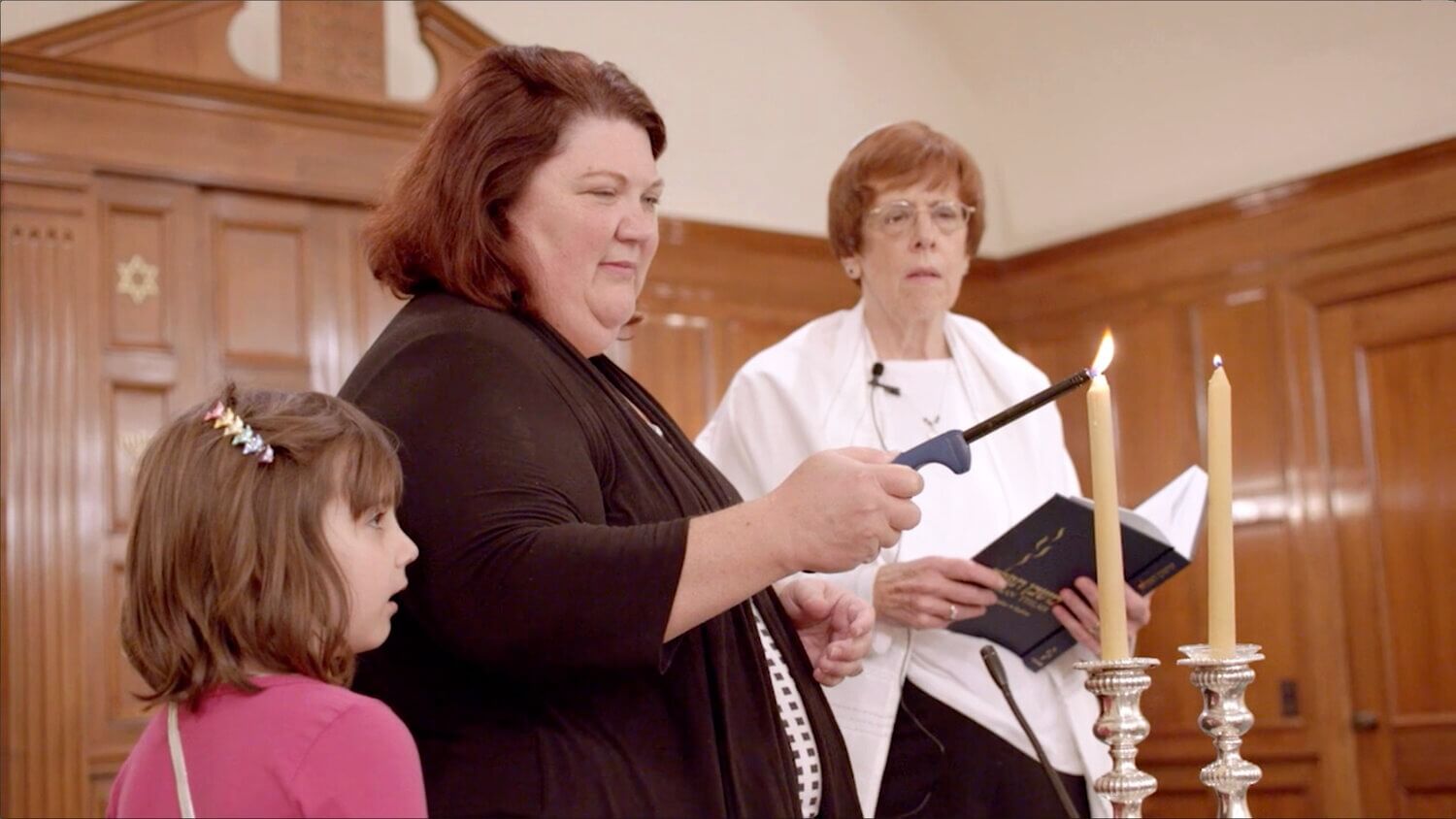 Karen Arenson and her daughter Emily light the Shabbat candles at Temple Emanu-El in Dothan, Alabama, as Rabbi Lynne Goldsmith looks on, in a scene from the 2016 documentary <i>There Are Jews Here</i>.