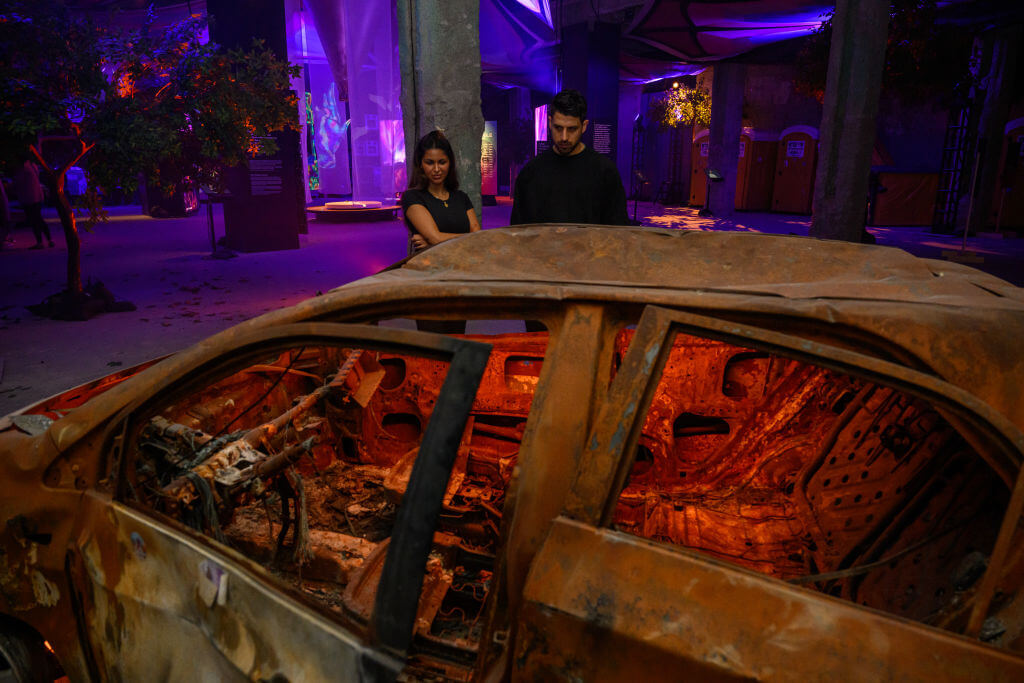 Nova survivor Natalie Sanandaji, and Reef Peretz, Chairman of the Nova Foundation, look at destroyed cars taken from the Nova festival at <i>The Nova Music Festival Exhibition</i> in April 2024 in New York City.