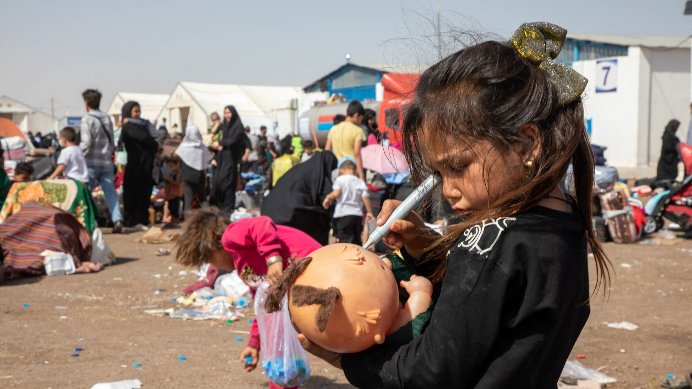 A young girl holds a broken doll among newly arrived Afghan returnees at a border crossing with Iran on July 4. 