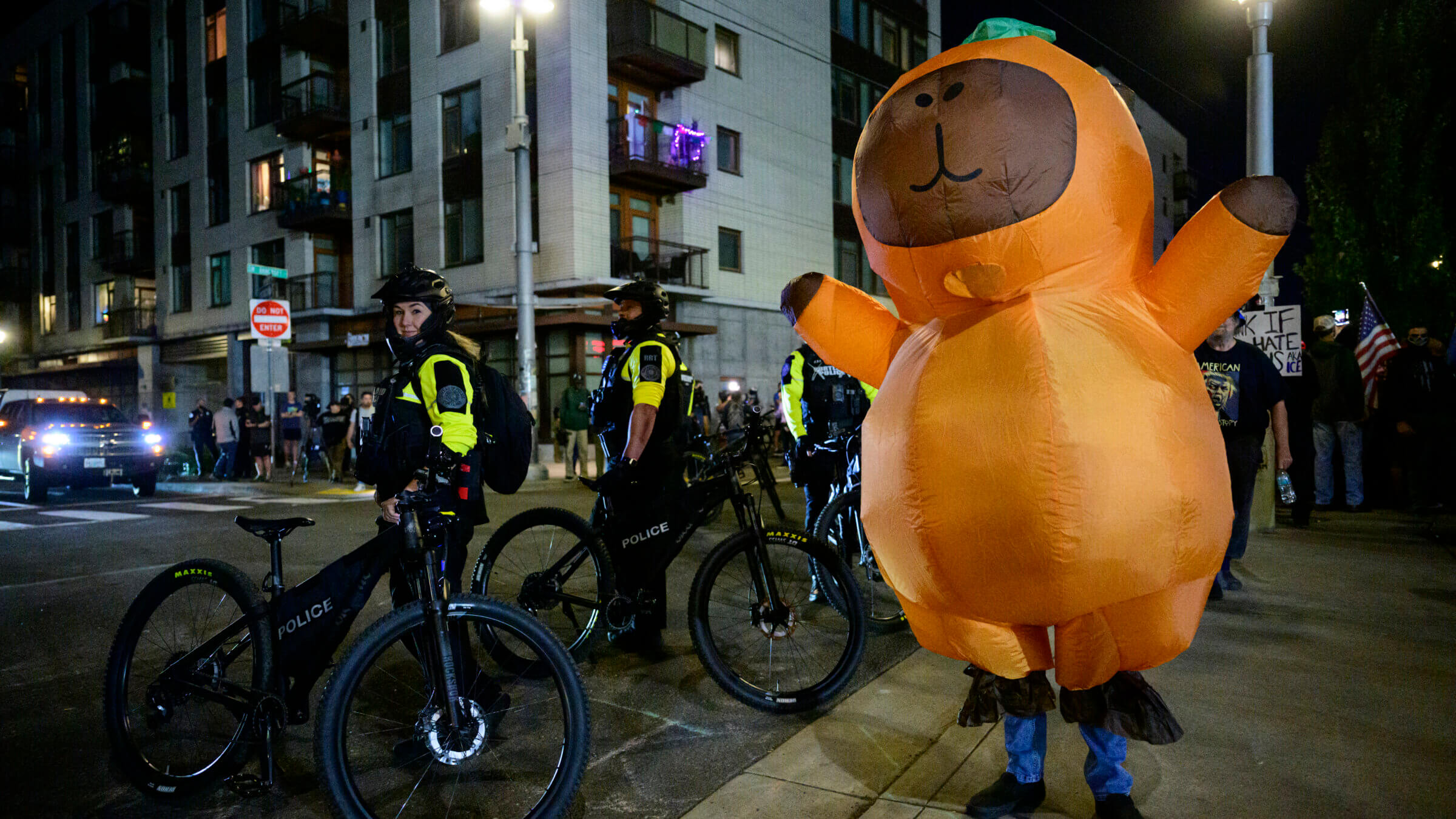 Portland Police officers stand watch as protesters demonstrate near an ICE facility.