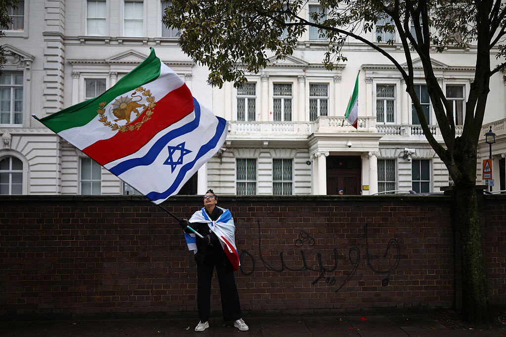 An anti-Iranian regime protester waves the Iranian flag from before the 1979 revolution with the lion and sun emblems with an Israeli flag outside the Iranian Embassy in central London, Jan. 9.