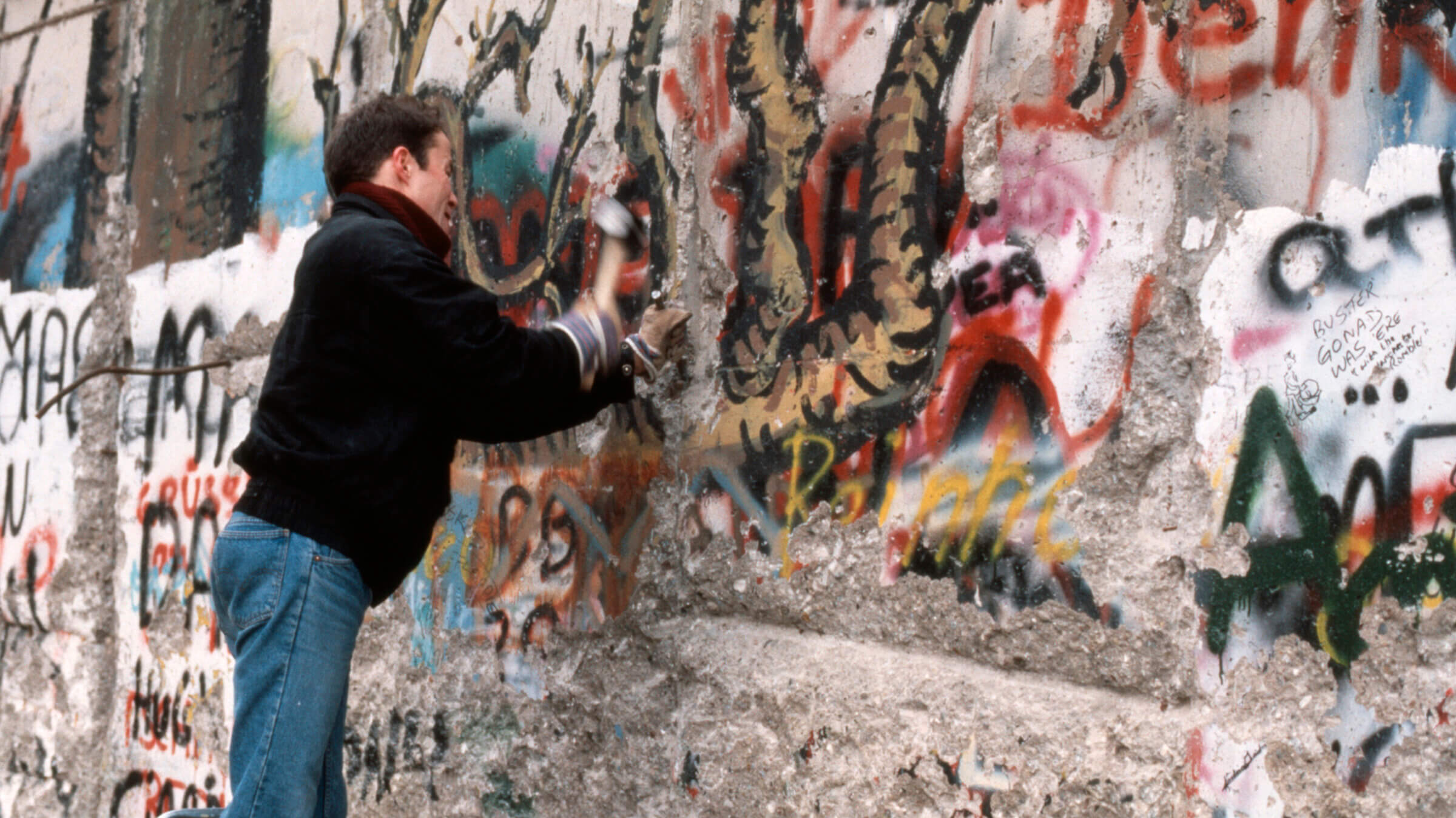 A young man chisels away at the Berlin Wall, 1989.