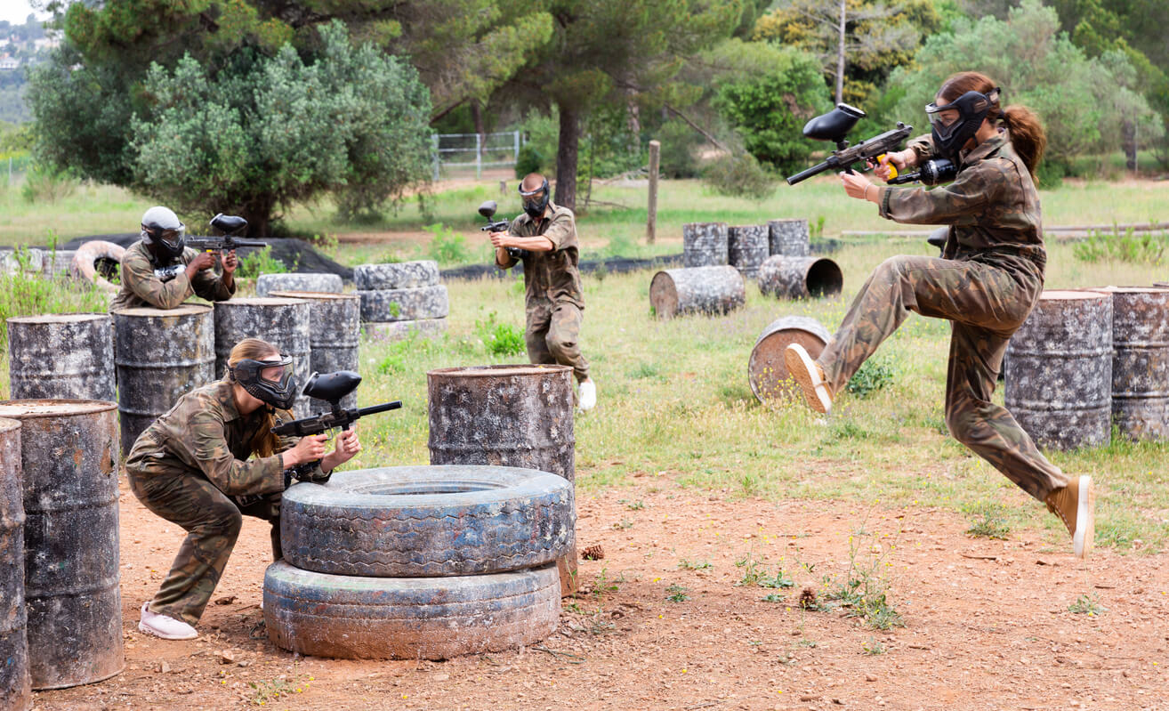 A group plays paintball at an outdoor shooting range. 