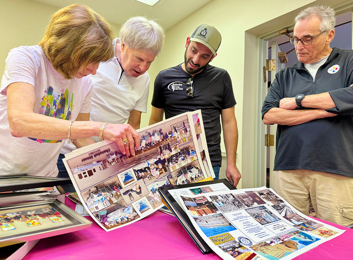 Temple B'nai Israel members Debbie Iszauk, Steve Mayer and Dick Leffel sift through old photographs from the synagogue to give to Nik Jakobs (in black T-shirt) to put in his museum honoring the shul.