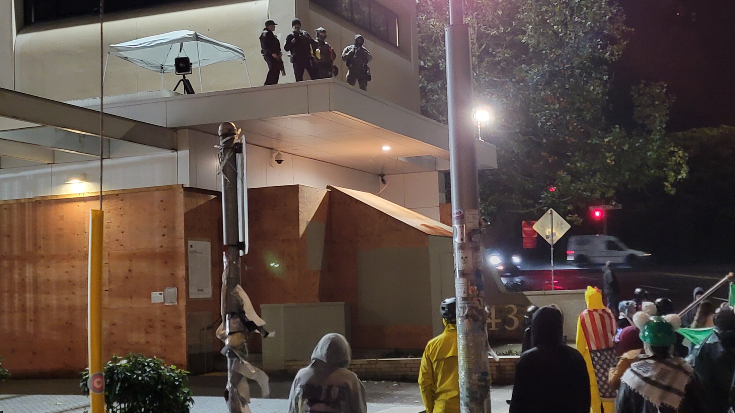 אַ גרופּע פֿעדעראַלע „אײַס“־אַגענטן, אױפֿן דאַך פֿונעם „אײַס“־בנין אין פּאָרטלאַנד, אָרעגאָן, וואַכן איבער אַ גרופּע דעמאָנטסראַנטן, דעם 25סטן אָקטאָבער 

