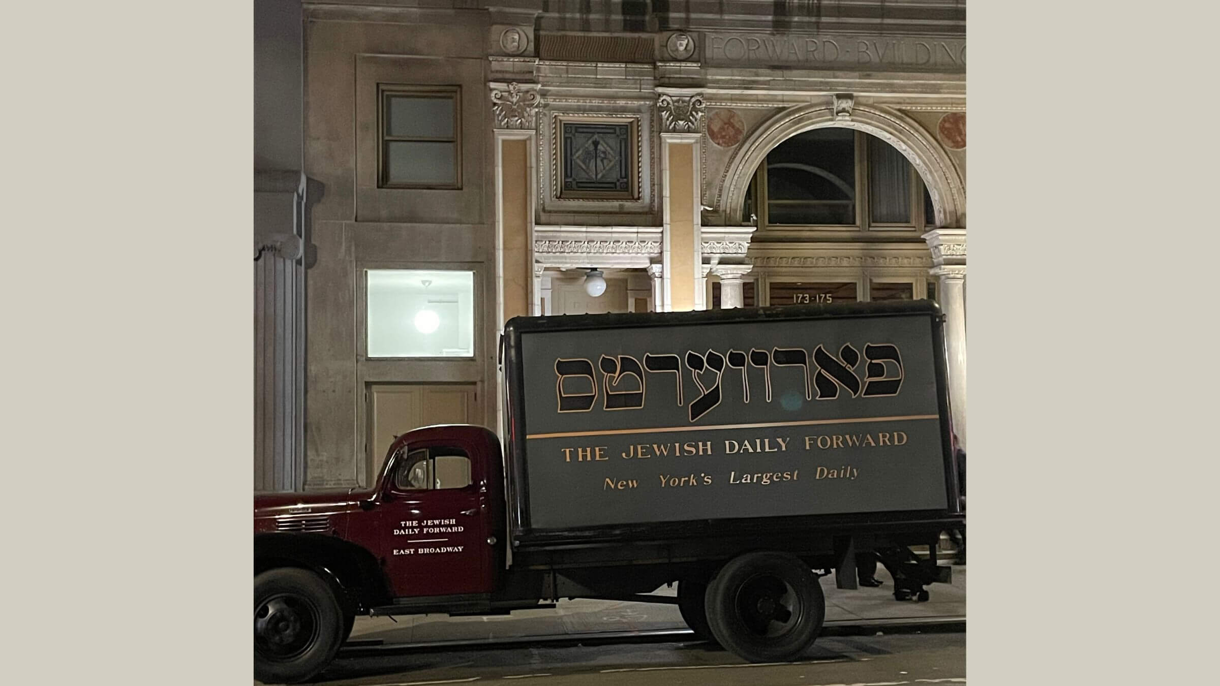 A truck with <i>Forverts</i> written on the side in Yiddish in front of the Forward Building on East Broadway.